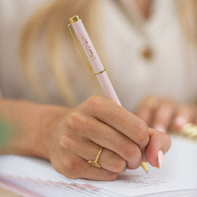 A hand holds a premium pale pink and gold metal pen.