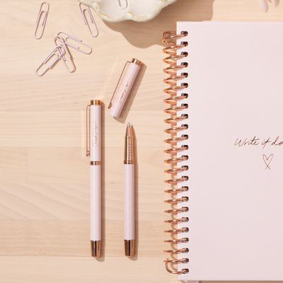 Three Premium metal ballpoint pens in Rose Gold and Pink lie on a desk