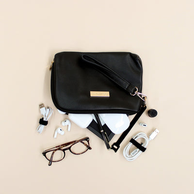 Black faux leather cable organiser bag with zip, removable strap, tech loops and multiple storage pockets. Filled with air pods, mouse, charging cables and glasses.