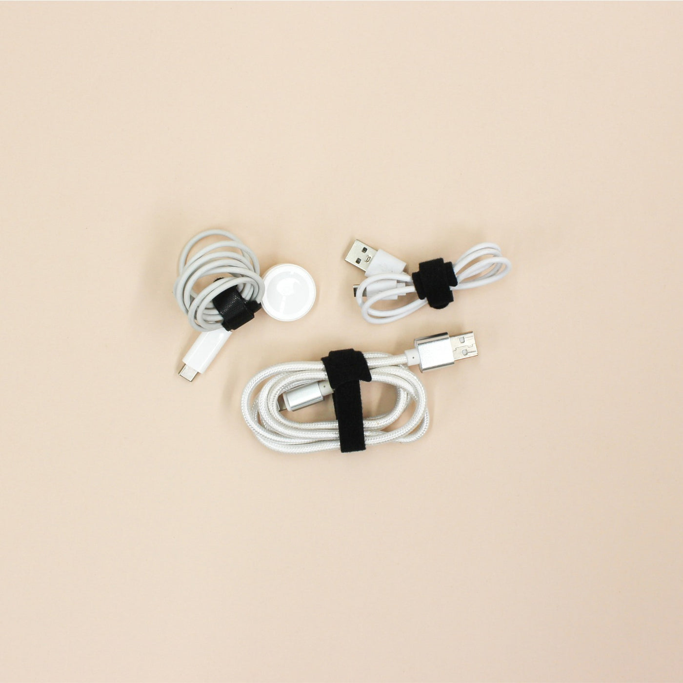Set of white charging cables with black velcro loop ties on a beige background