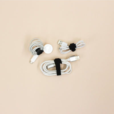Set of white charging cables with black velcro loop ties on a beige background